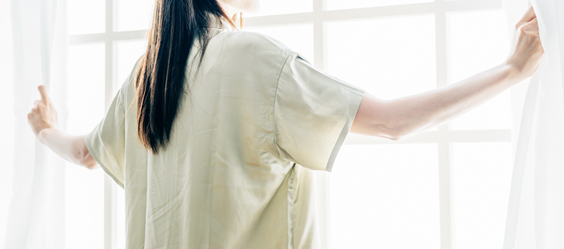 カーテンを開ける女性